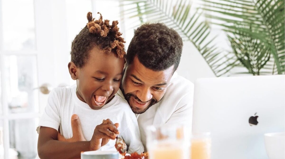 A father looking for EAP alternatives on his laptop while helping his son eat.