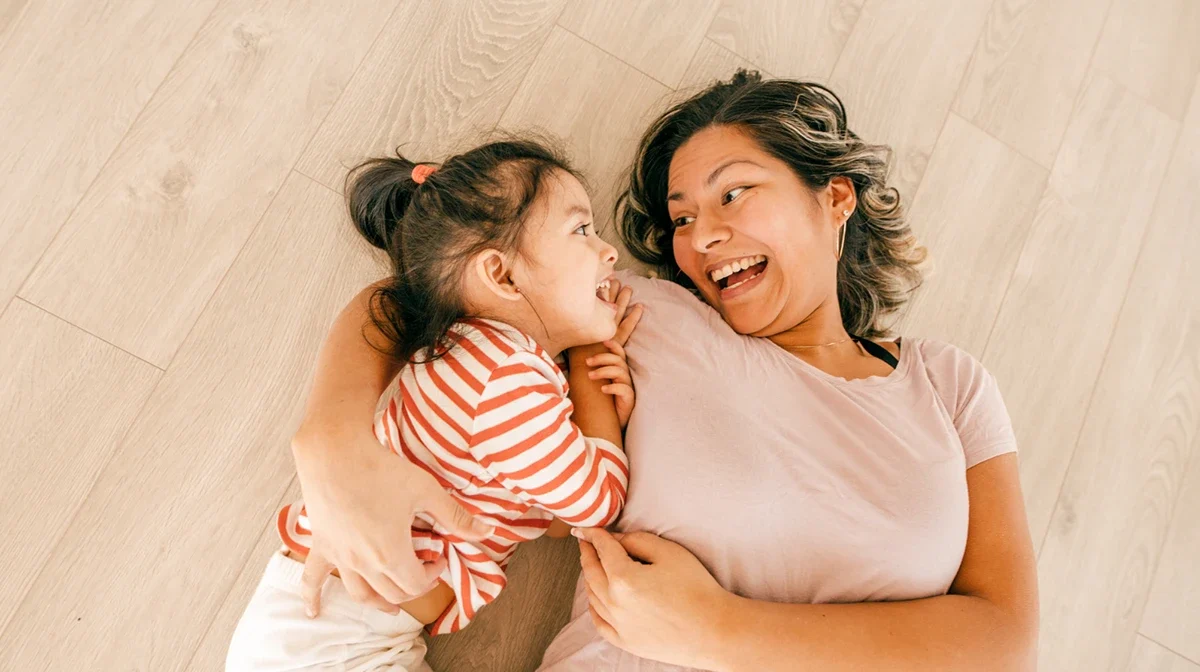 Mother and daughter hugging while laying on the floor illustrating the concept of an effective family care solution.