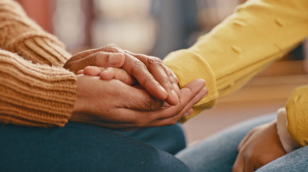 Close-up of two women holding hands.