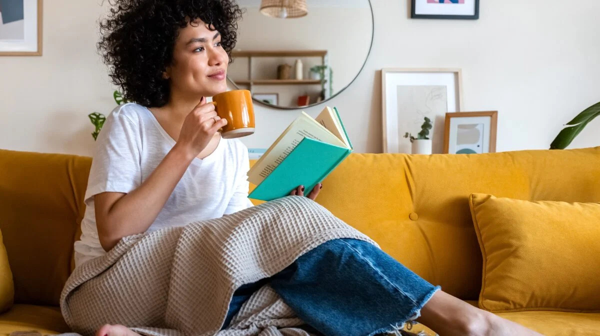 Woman reading top 10 self-care tips at home.