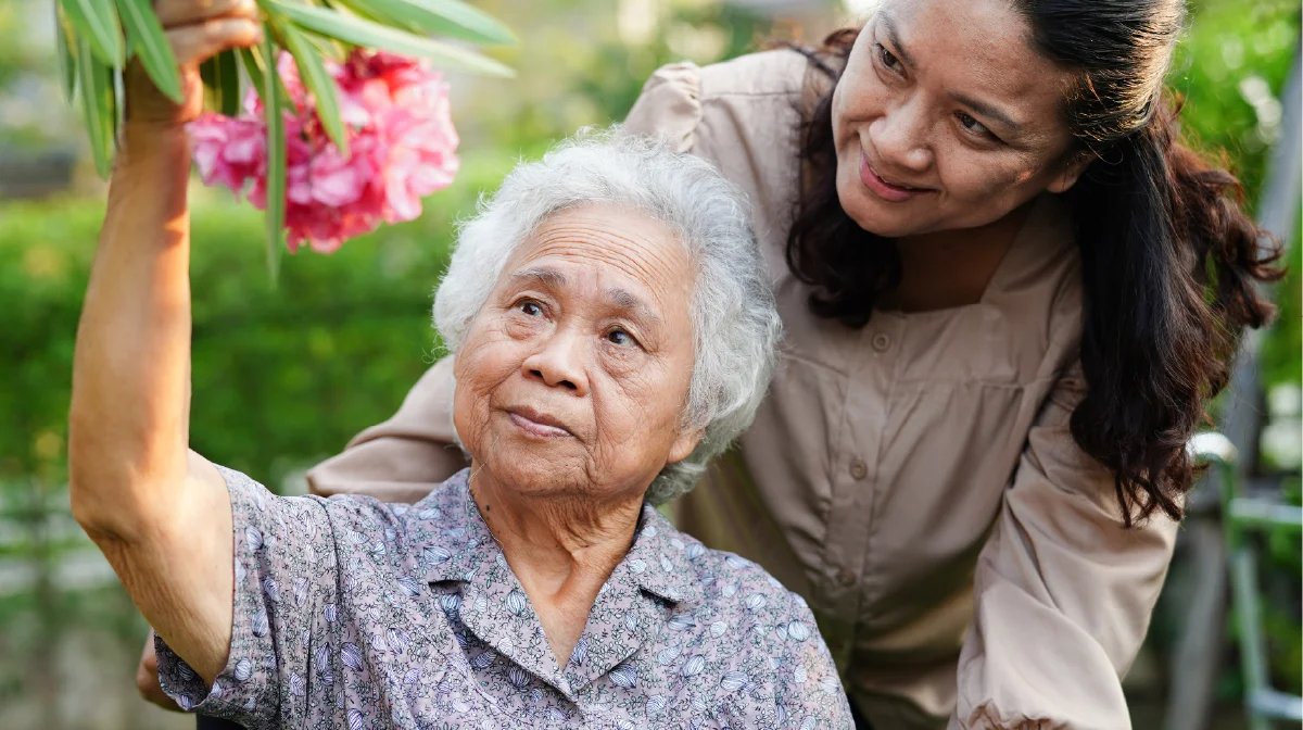 DEI caregiver helping an older woman.