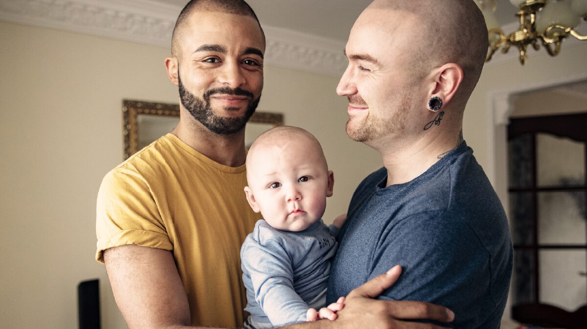 Same sex couple and their child illustrating the idea of modern family care.