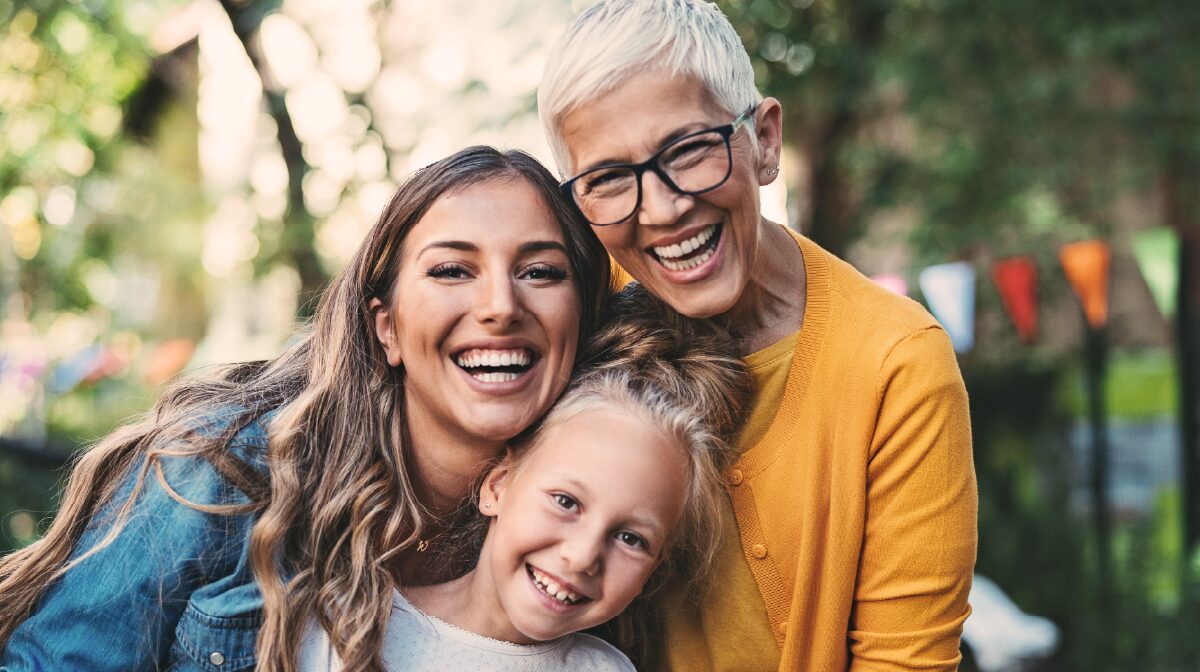 Sandwich generation caregiver posing for a photo with her mother and daughter.