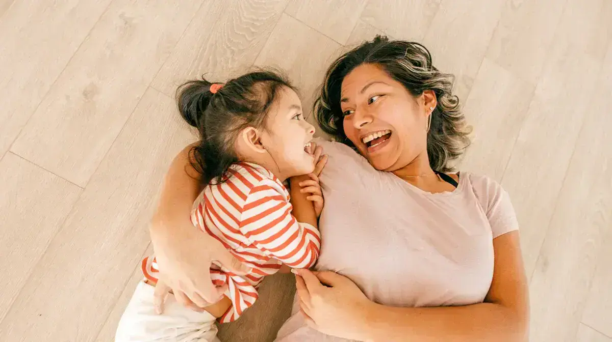 Mother and daughter hugging while laying on the floor illustrating the concept of an effective family care solution.