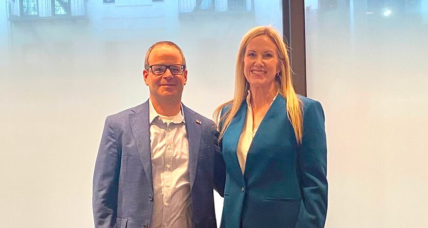 Man and woman in business attire posing for a photo at a healthcare conference.